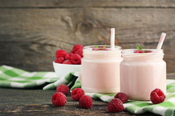Raspberries yogurt in jars on wooden table
