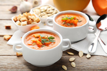 Pumpkin soup with seeds and parsley in plate on wooden table