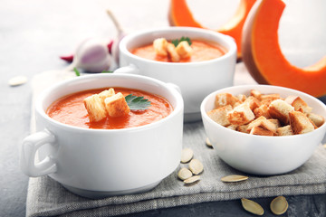 Pumpkin soup with rusks and parsley in plate on wooden table