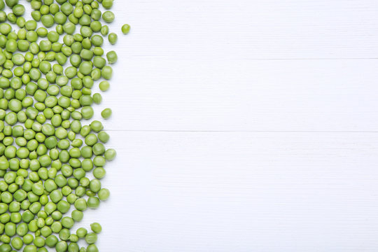 Fresh green peas on white wooden table