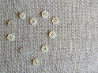 Buttons on beige natural linen fabric background. Colourful buttons. Heart.