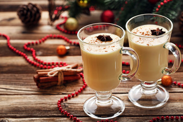 Eggnog in glasses with cinamon and star anise on wooden table