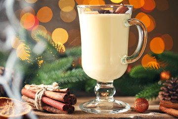 Eggnog in glass with cinamon and star anise on lights background
