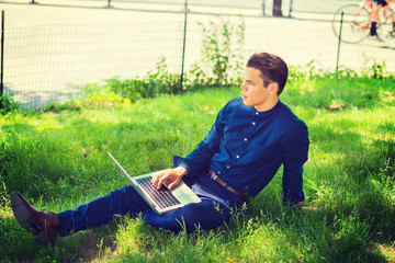 Businessman traveling, working in New York. Wearing blue collarless shirt, a college student sitting on green grasses on campus, reading, thinking, working on laptop computer. .