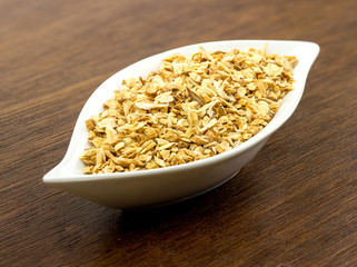 Plate full of astragalus roots on wood background