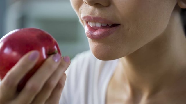 Hungry girl with great appetite biting big juicy apple, healthy snack at work