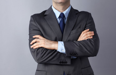 Businessman standing with arms crossed, isolated on gray background