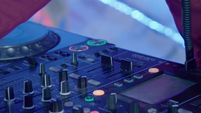 Male DJ play the music on the mixing console in the nightclub, closeup slow motion shot.