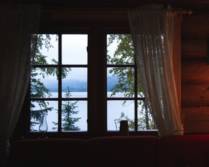 Window view on the lake in a wooden house in Norway