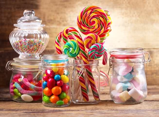 Tuinposter Colorful candies, lollipops and marshmallows  in a glass jars © Nitr