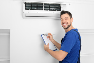 Male technician checking air conditioner indoors