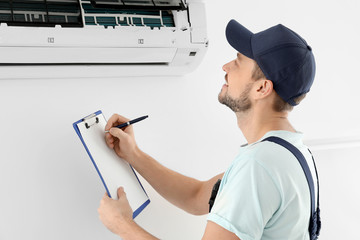 Male technician checking air conditioner indoors