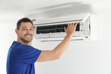 Man cleaning air conditioner indoors