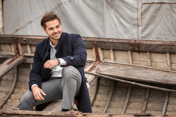 Young handsome man sitting in old boat, outdoors