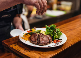 Stir fried beef steak served with vegetable side dish and salad topping with balsamic dressing.