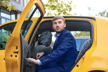 Young businessman getting out of taxi car