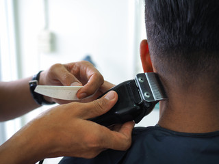 man getting haircut at barber shop. Hairdresser cutting hair of customer at salon.