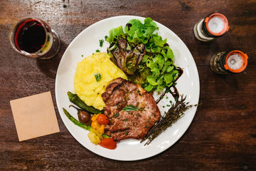 Stir fried pork steak served with vegetable side dish, salad and mash potato topping with balsamic dressing and red wine.