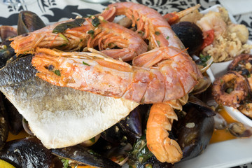 The plate of maltese seafood - freshly caught and grilled octopus tentacles, calamari rings in tempura, giant shrimps, clams, fish fillets and mussels 