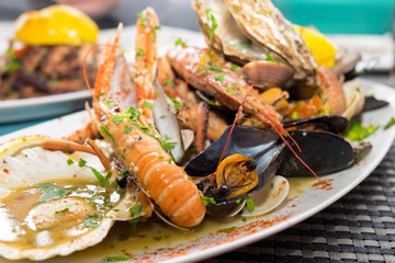 The plate of maltese seafood - freshly caught and grilled octopus tentacles, calamari rings in tempura, giant shrimps, clams, fish fillets and mussels 
