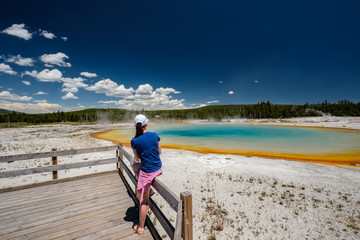 Fototapeta premium Woman tourist overlooking thermal spring in Yellowstone
