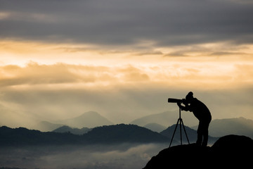 silhouette of a photographer who shoots a sunset - obrazy, fototapety, plakaty