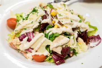 Caesar salad with roasted chicken breast, parmesan cheese, lettuce leaf, cherry tomatoes, corn and cheese sauce