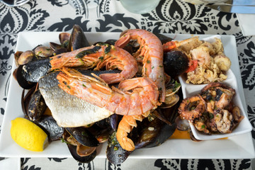 The plate of maltese seafood - freshly caught and grilled octopus tentacles, calamari rings in tempura, giant shrimps, clams, fish fillets and mussels 