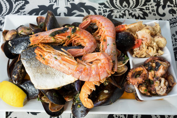 The plate of maltese seafood - freshly caught and grilled octopus tentacles, calamari rings in tempura, giant shrimps, clams, fish fillets and mussels 