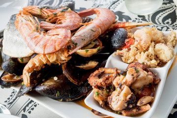 The plate of maltese seafood - freshly caught and grilled octopus tentacles, calamari rings in tempura, giant shrimps, clams, fish fillets and mussels 