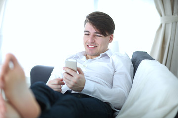 Handsome young man using smartphone at home
