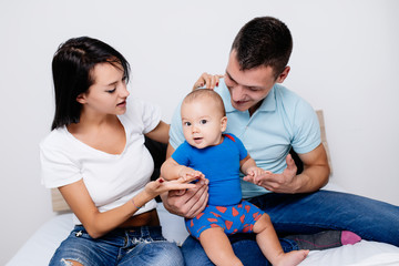 Mother and father enjoying and relaxing with their baby on bed. 