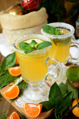 Yellow cocktail in an Irish mug decorated with sugar border and mint surrounded by Christmas attributes