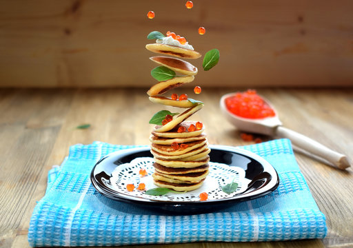 Flying Pancakes, Red Caviar And Basil Leaves. Levitating Food On A Wooden Background