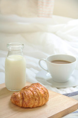 Bed breakfast with coffee cup, croissants and milk in bed, cozy relaxing morning coffee, holidays and winter concept