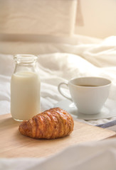 Bed breakfast with coffee cup, croissants and milk in bed, cozy relaxing morning coffee, holidays and winter concept