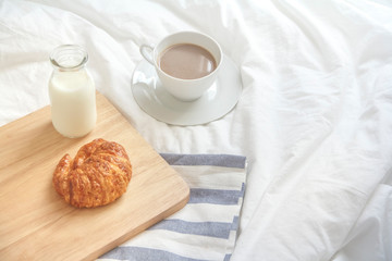 Bed breakfast with coffee cup, croissants and milk in bed, cozy relaxing morning coffee, holidays and winter concept