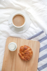 Bed breakfast with coffee cup, croissants and milk in bed, cozy relaxing morning coffee, holidays and winter concept
