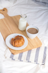 Bed breakfast with coffee cup, croissants and milk in bed, cozy relaxing morning coffee, holidays and winter concept