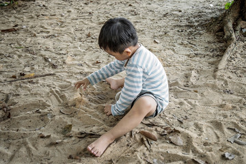 Obraz na płótnie Canvas cute asian boy plays with sand