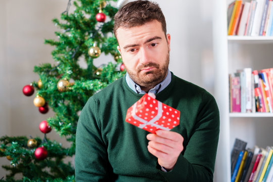 Funny face of a man disappointed by the small gift box