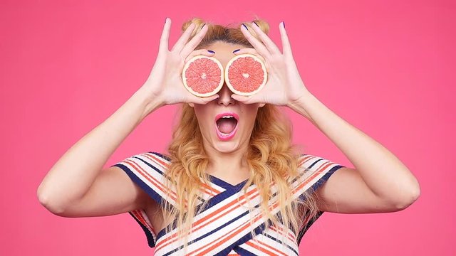Happy young woman with two half of juicy grapefruit instead eyes