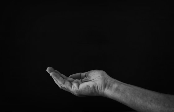 black and white image of open male hand begging for help.