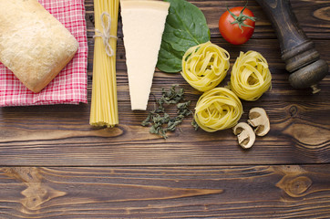 Italian food ingredients: pasta, tomato, spinach, pepper, porcini on wooden background