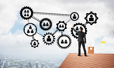 Businessman on house roof presenting teamwork and connection concept. Mixed media