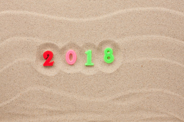Fototapeta na wymiar Figures 2018 laid out on the sand.
