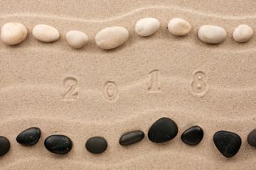 Fototapeta na wymiar Figures 2018 year imprints on the sand.