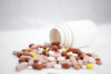 Colorful pills laying on the white background with empty bottles