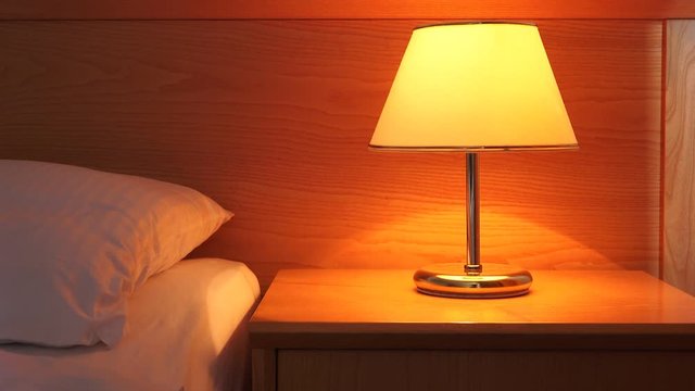 Vintage lamp on night table in hotel room. Retro styled bedroom interior.
