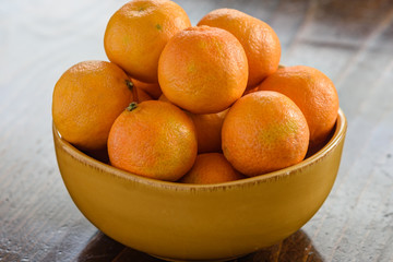Bowl of citrus fruit with natural light on wood table